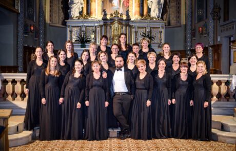 LadiniaFestival international de chœurs amateurs en France. Chorale de femmes en concert dans une église ornée d'or et d'architecture classique.